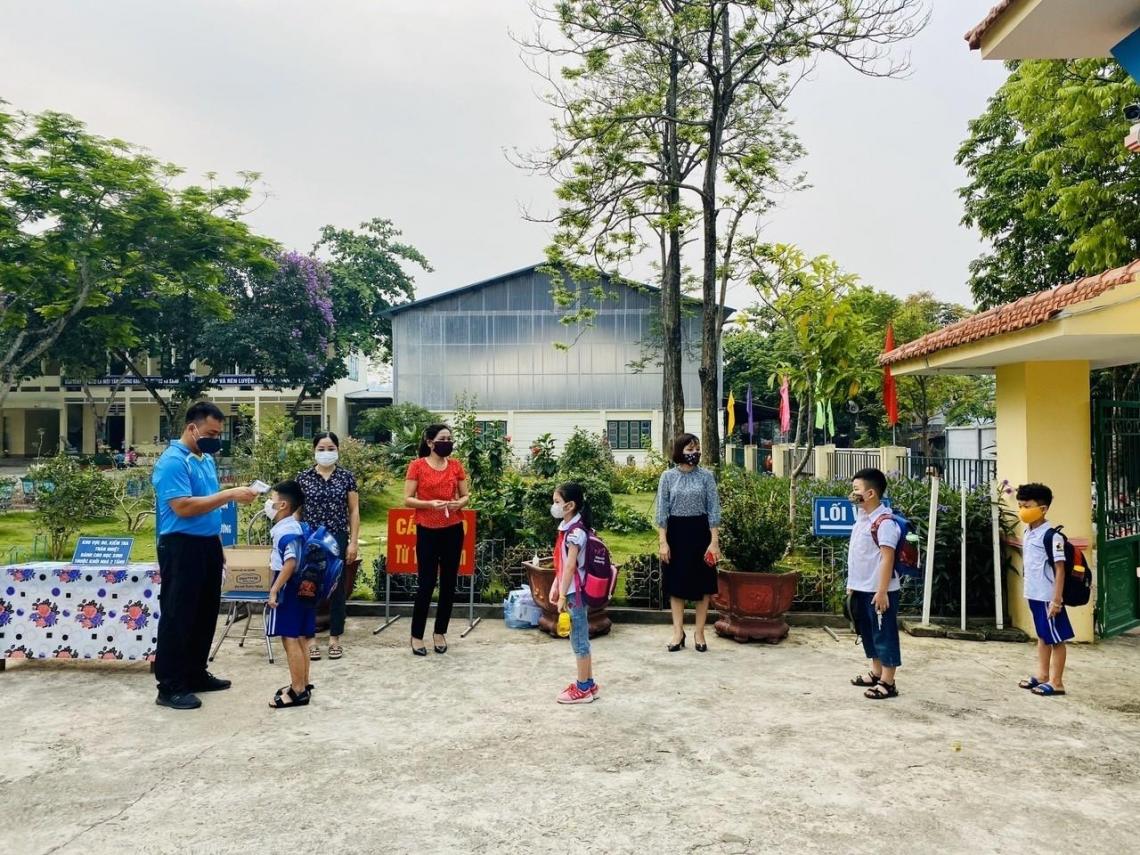 Children lined up for temperature checks as they enter their school