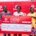 Maureen Bus-Moses (middle), a 2Moorch Money promo weekly prize winner, receives the cheque of GH₵20,000 with her mother and sister at the Takoradi Market Circle